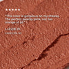 Close-up of a peachy-pink makeup product with a customer review on a white background