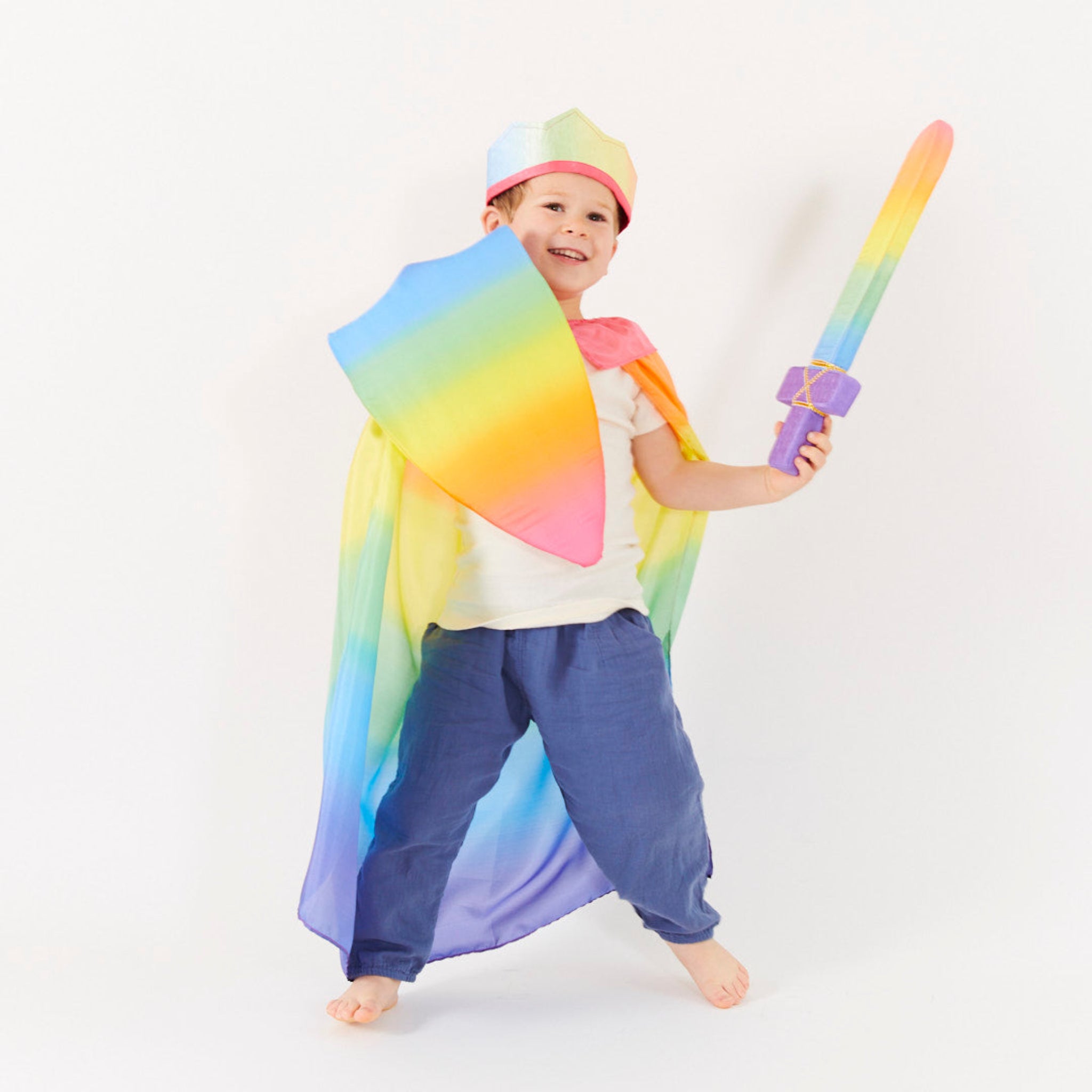 Child wearing a rainbow-colored cape and holding a sword against a white background