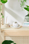 Wooden shelf with decorative items and plants on a white wall