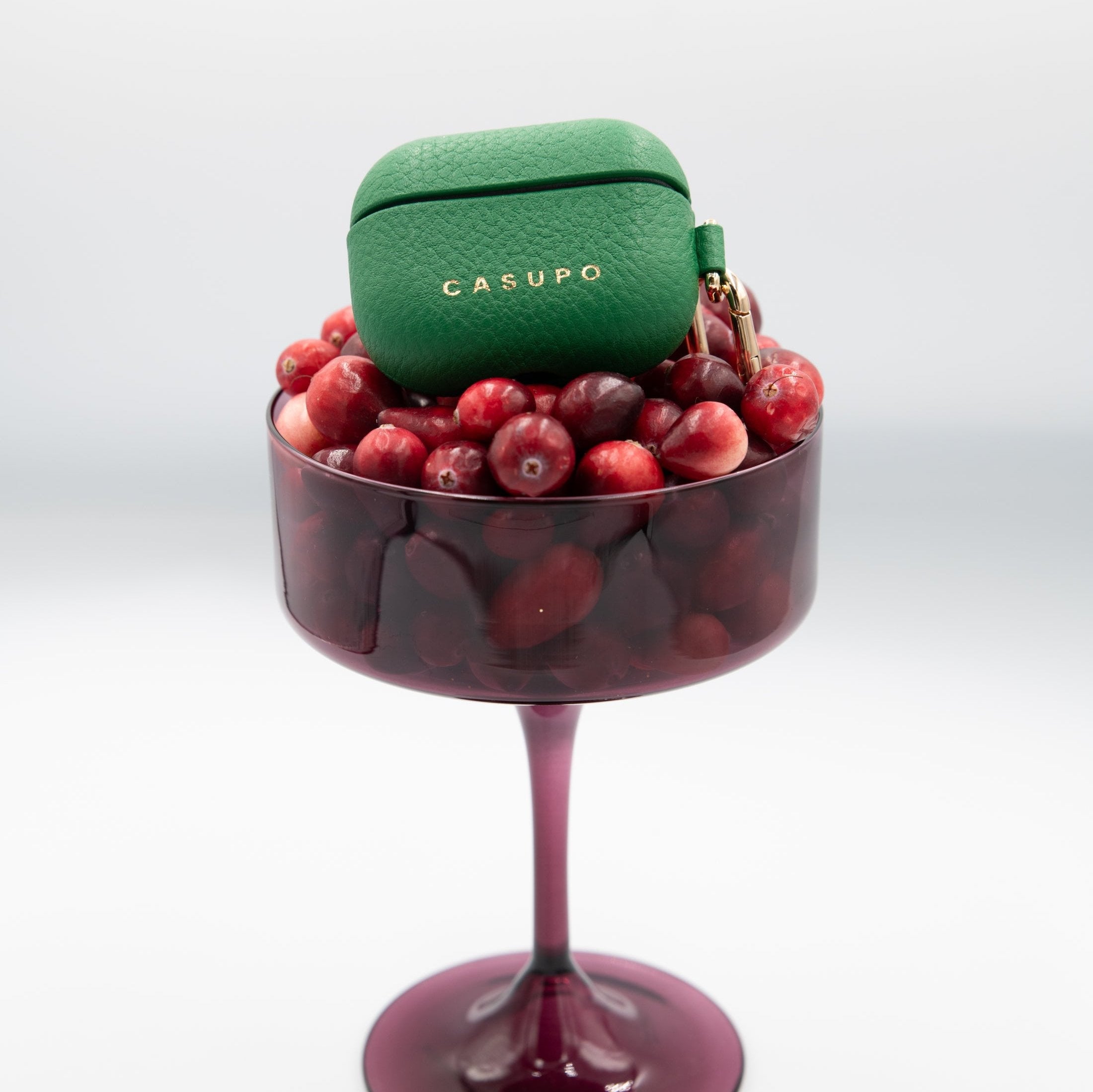 Green Casupo case on a glass filled with red berries on a white background