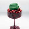 Green Casupo case on a glass filled with red berries on a white background