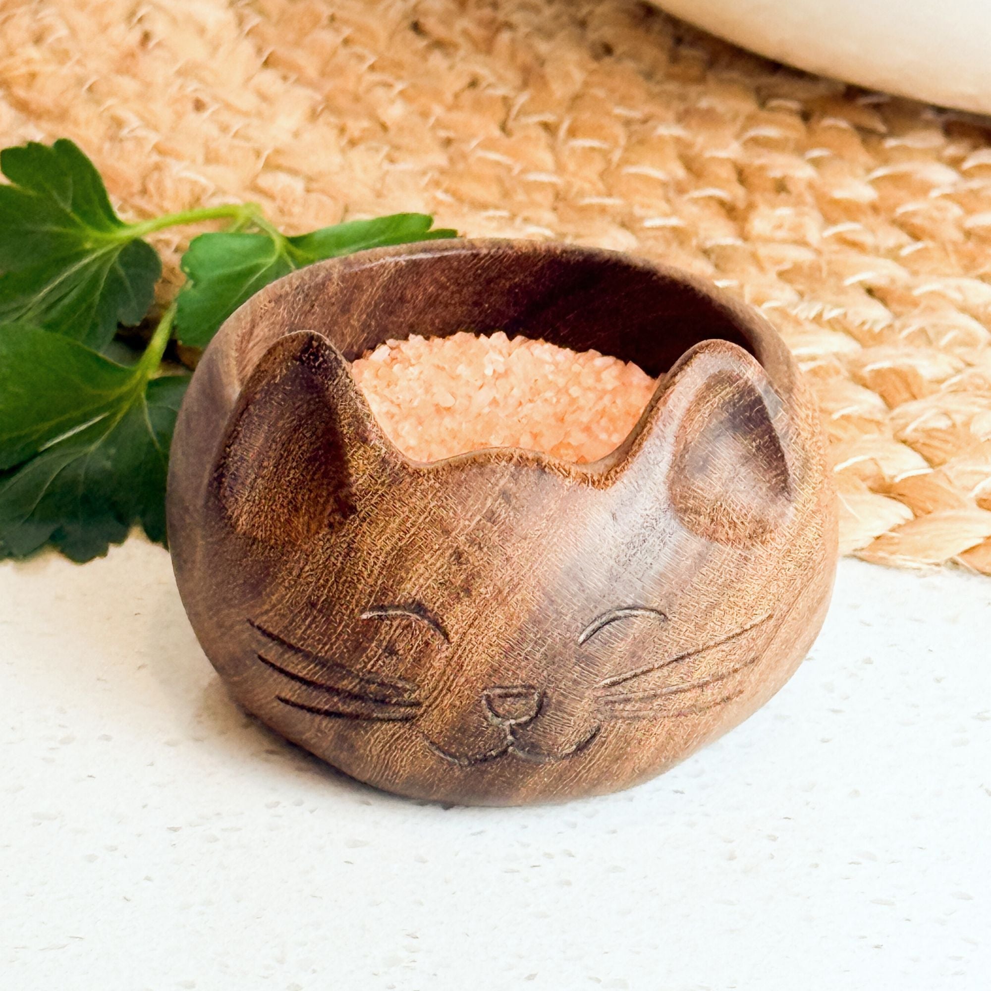 Wooden cat-shaped bowl with sand on a textured surface. Hand-carved cat salt bowl made from reclaimed wood by artisan families near Lake Atitlán, Guatemala. Holds 4 tbsp of salt or spices. Sustainable, unique, and perfect for cat lovers. A beautiful gift or kitchen essential.