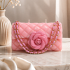 Pink quilted handbag-shaped candle with a rose detail on a marble surface.