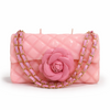 Pink candle shaped like a handbag with a rose and gold chain on a white background
