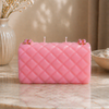 Pink quilted-pattern candle on a marble surface with decorative elements.