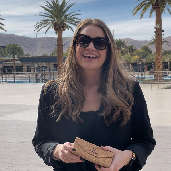 Woman holding a brown clutch with palm trees and mountains in the background
