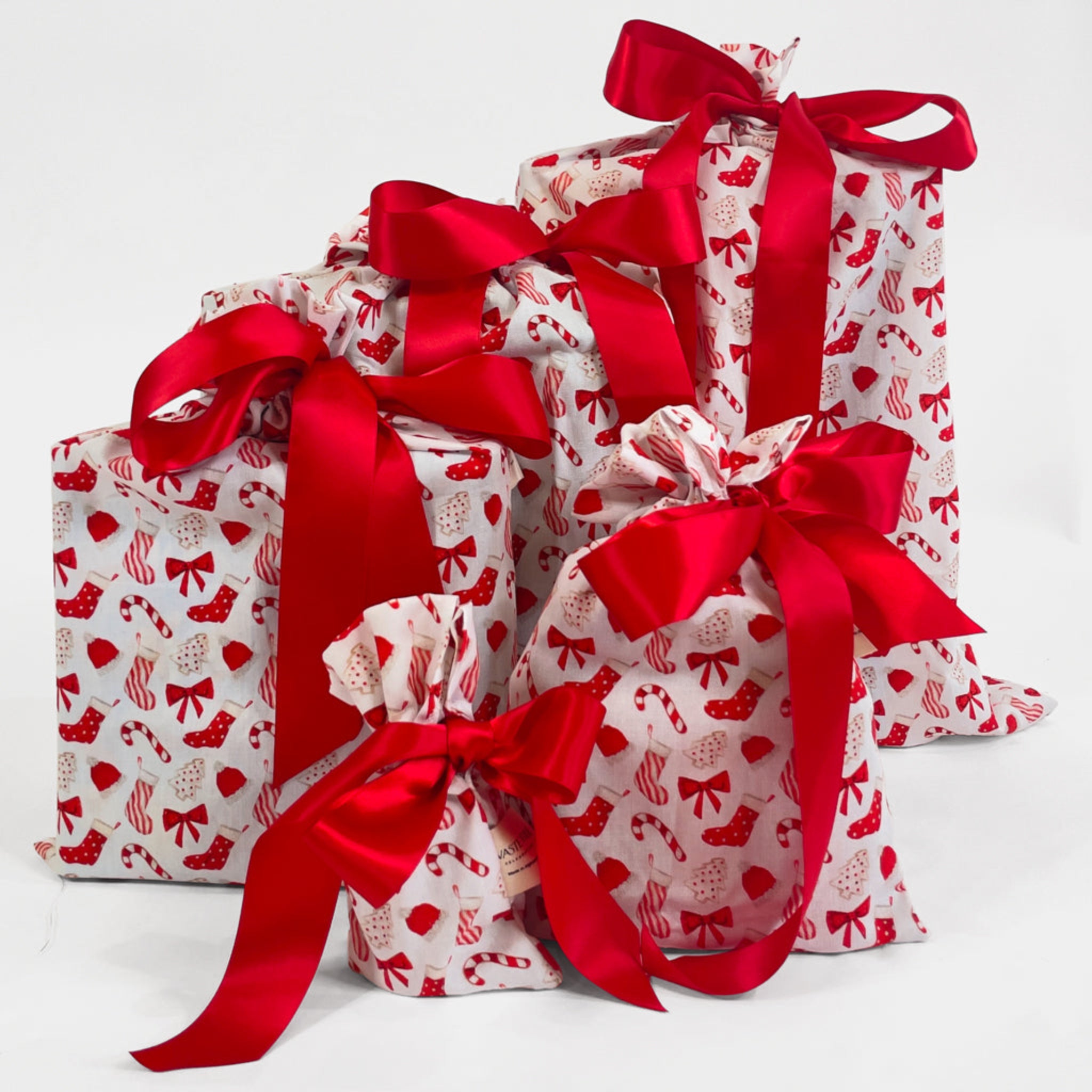 Three gift bags with red patterns and ribbons on a white background