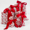 Three gift bags with red patterns and ribbons on a white background