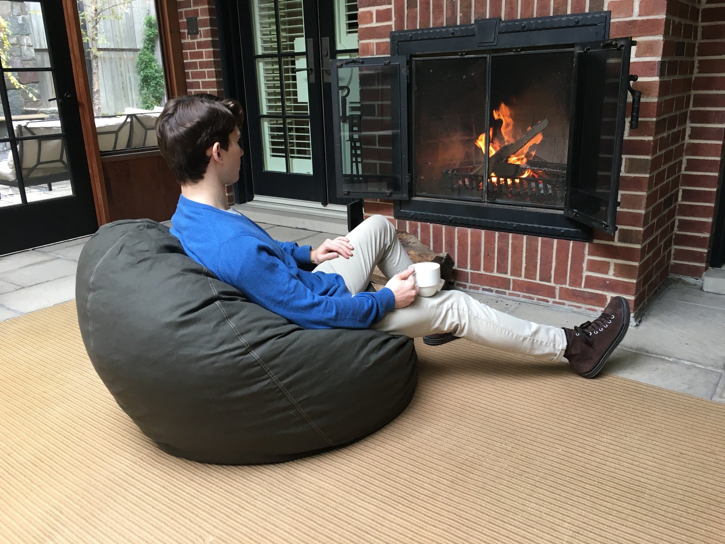 Person sitting on a bean bag chair in front of an outdoor fireplace.