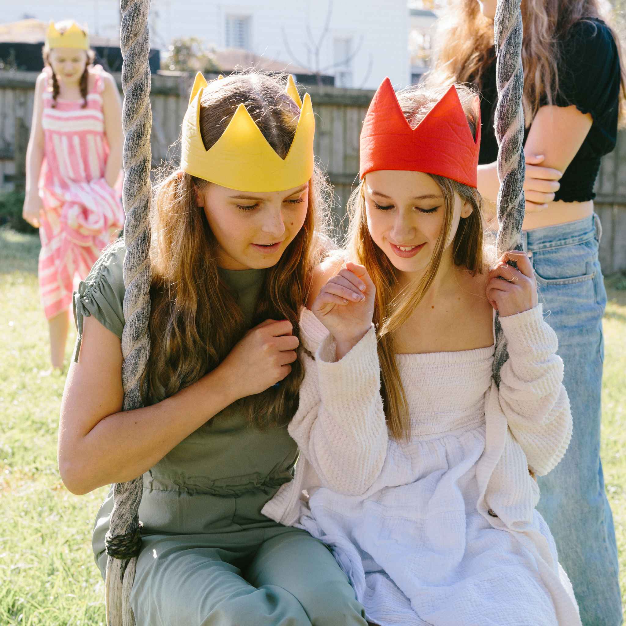 Two young girls wearing colorful fabric crowns outdoors.