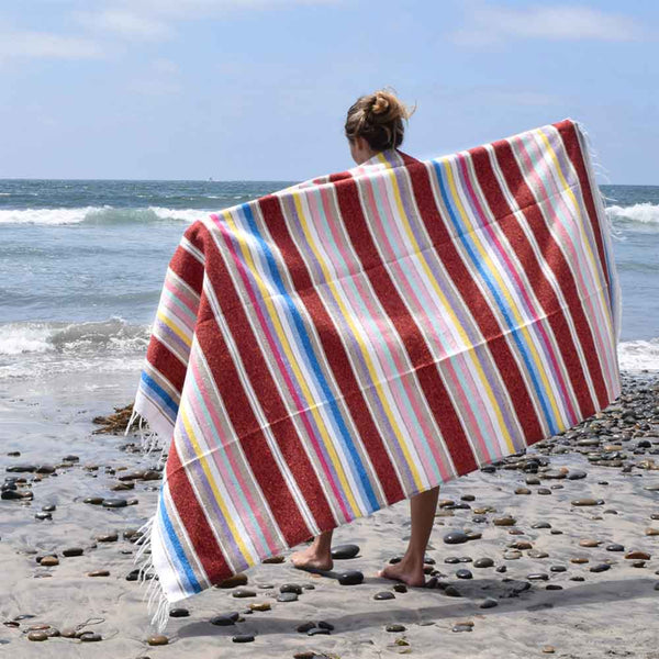 Person wrapped in a colorful striped towel on a beach