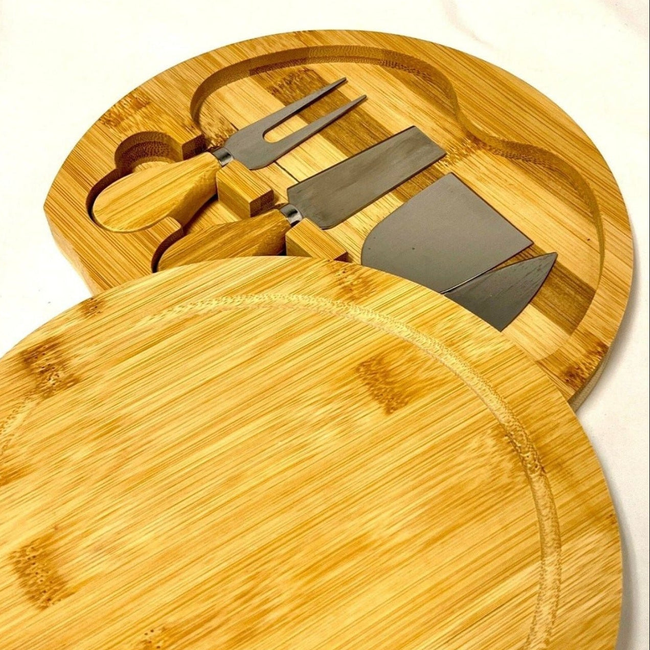 Round wooden cutting board with knife and fork set on a white background