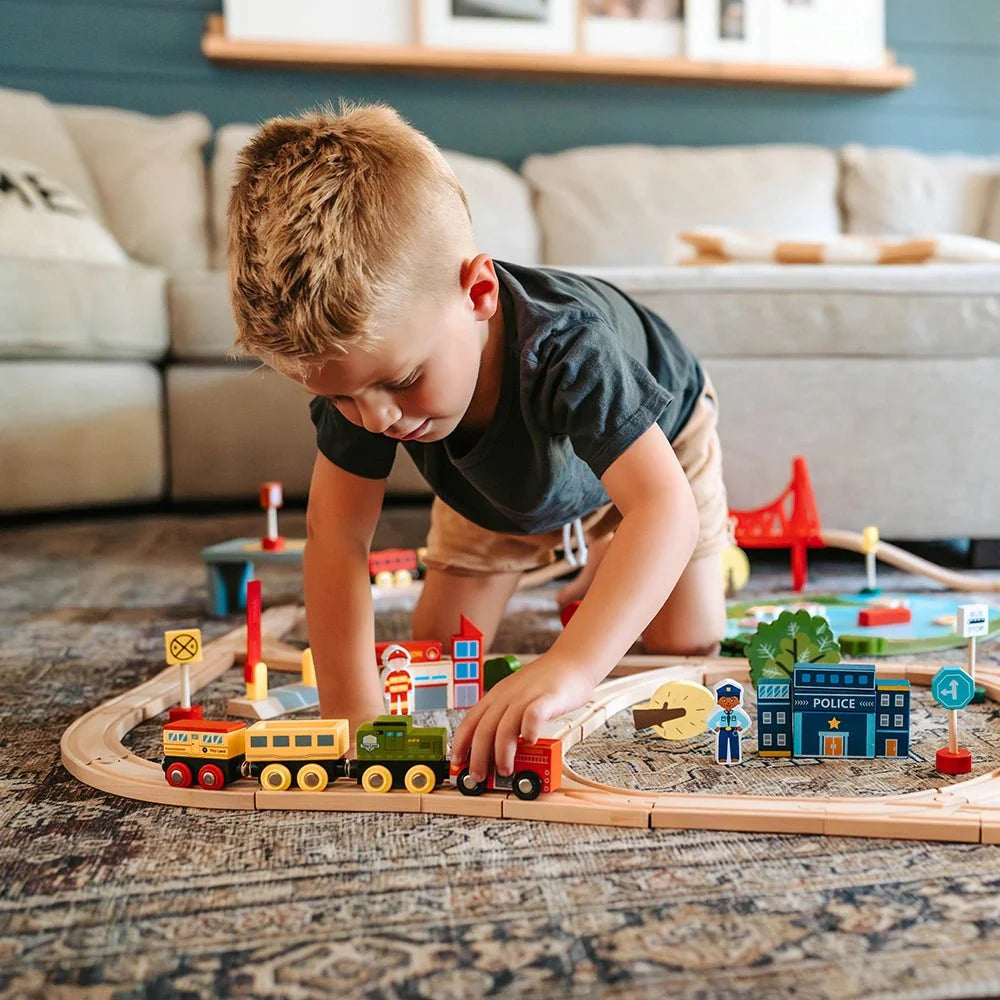 Child playing with a toy train set on a living room floor.