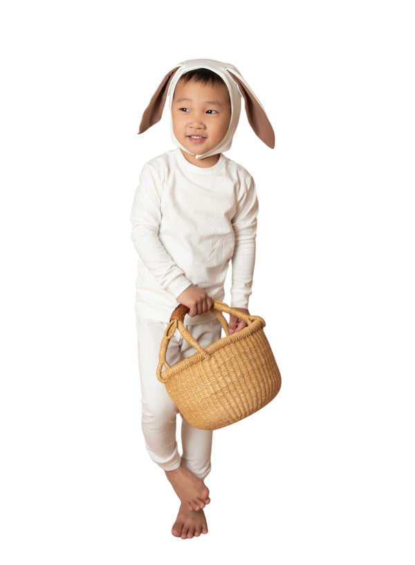 Child wearing a bunny costume holding a woven basket on a white background