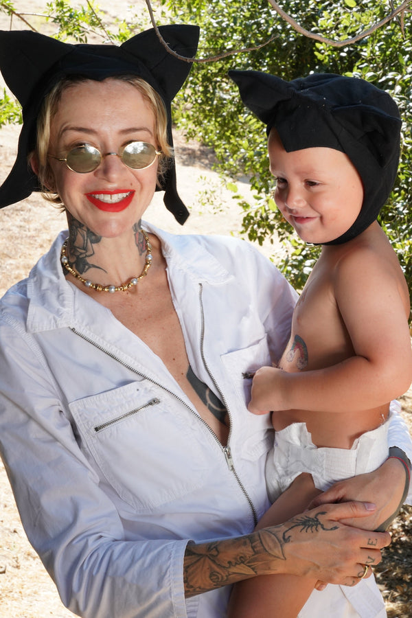 Woman holding a child both wearing black cat ears outdoors