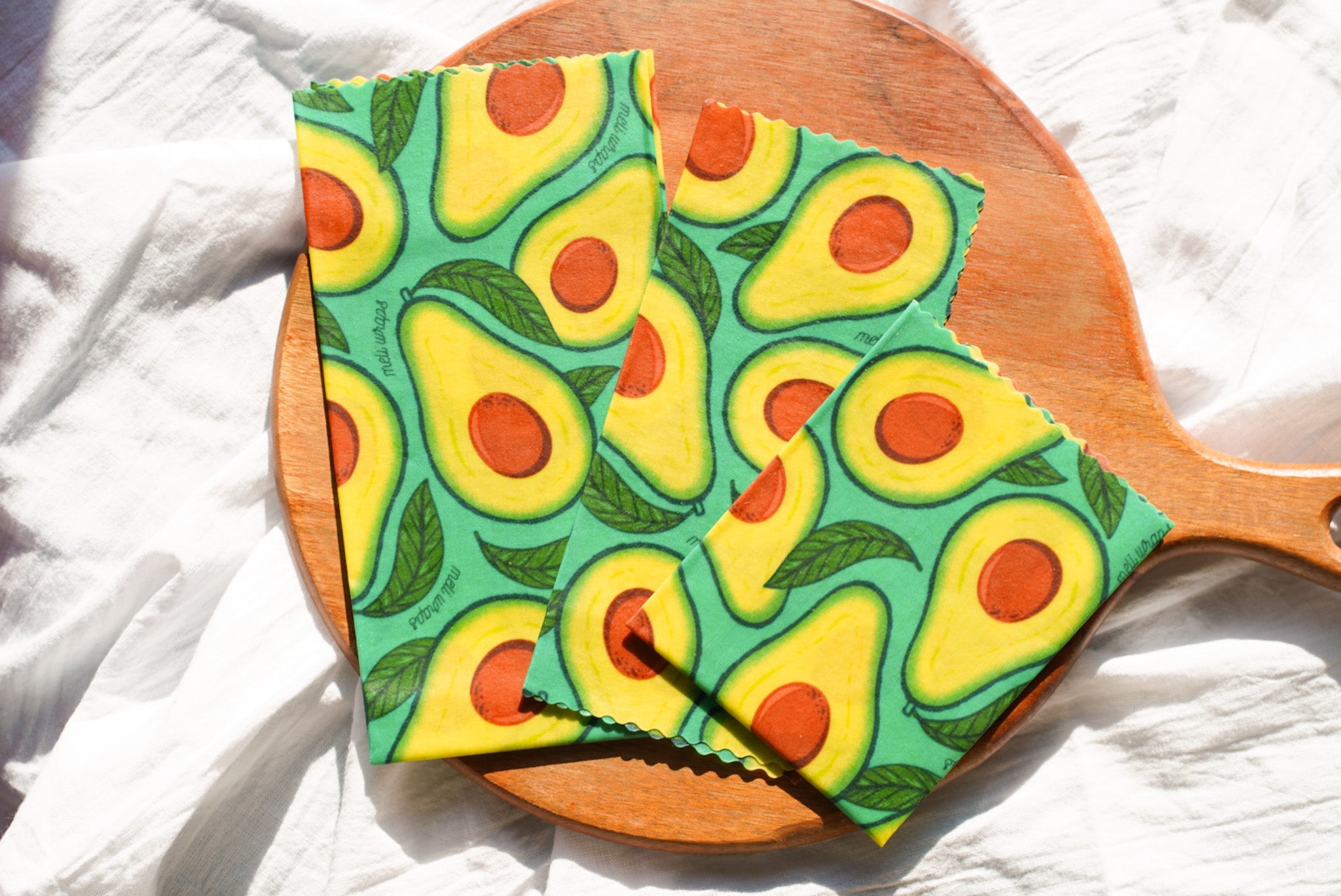 Avocado-patterned cloth on a wooden paddle with a white background
