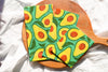 Avocado-patterned cloth on a wooden paddle with a white background