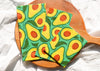 Avocado-patterned cloth on a wooden paddle with a white background