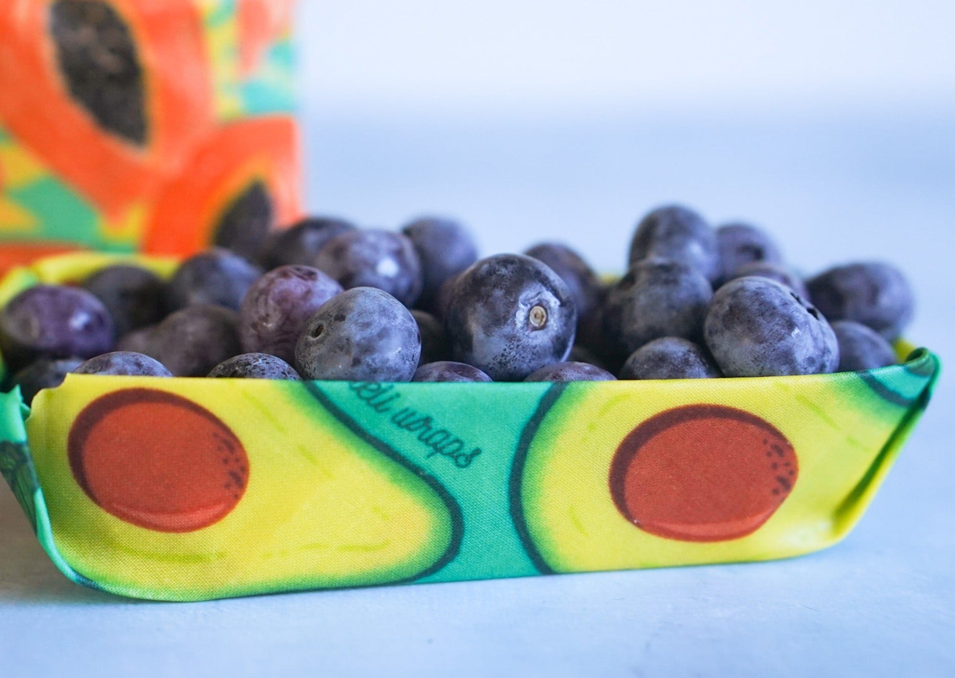 Avocado-shaped container with blueberries inside on a white background