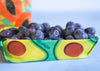 Avocado-shaped container with blueberries inside on a white background
