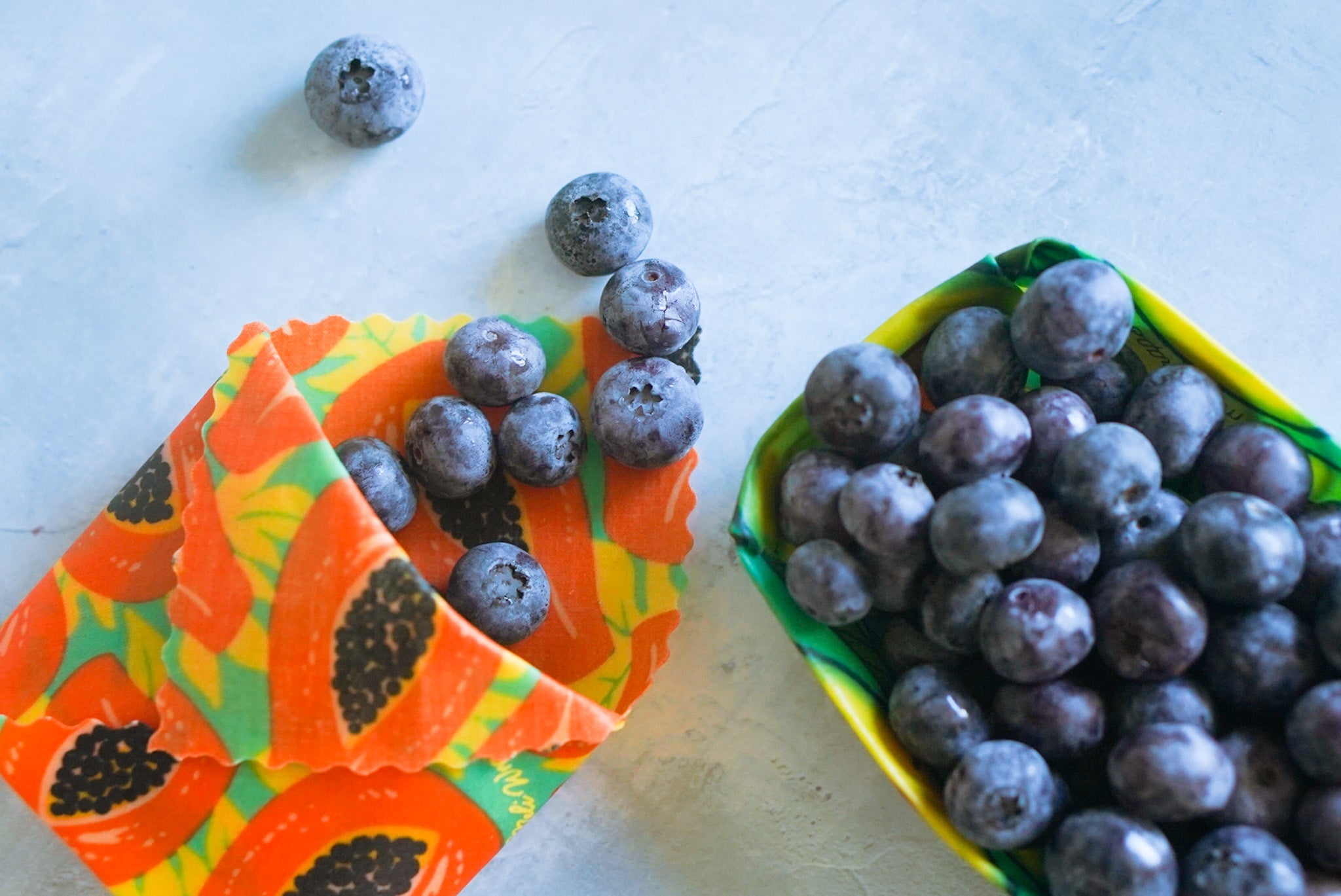 Blueberries in colorful paper containers on a white surface