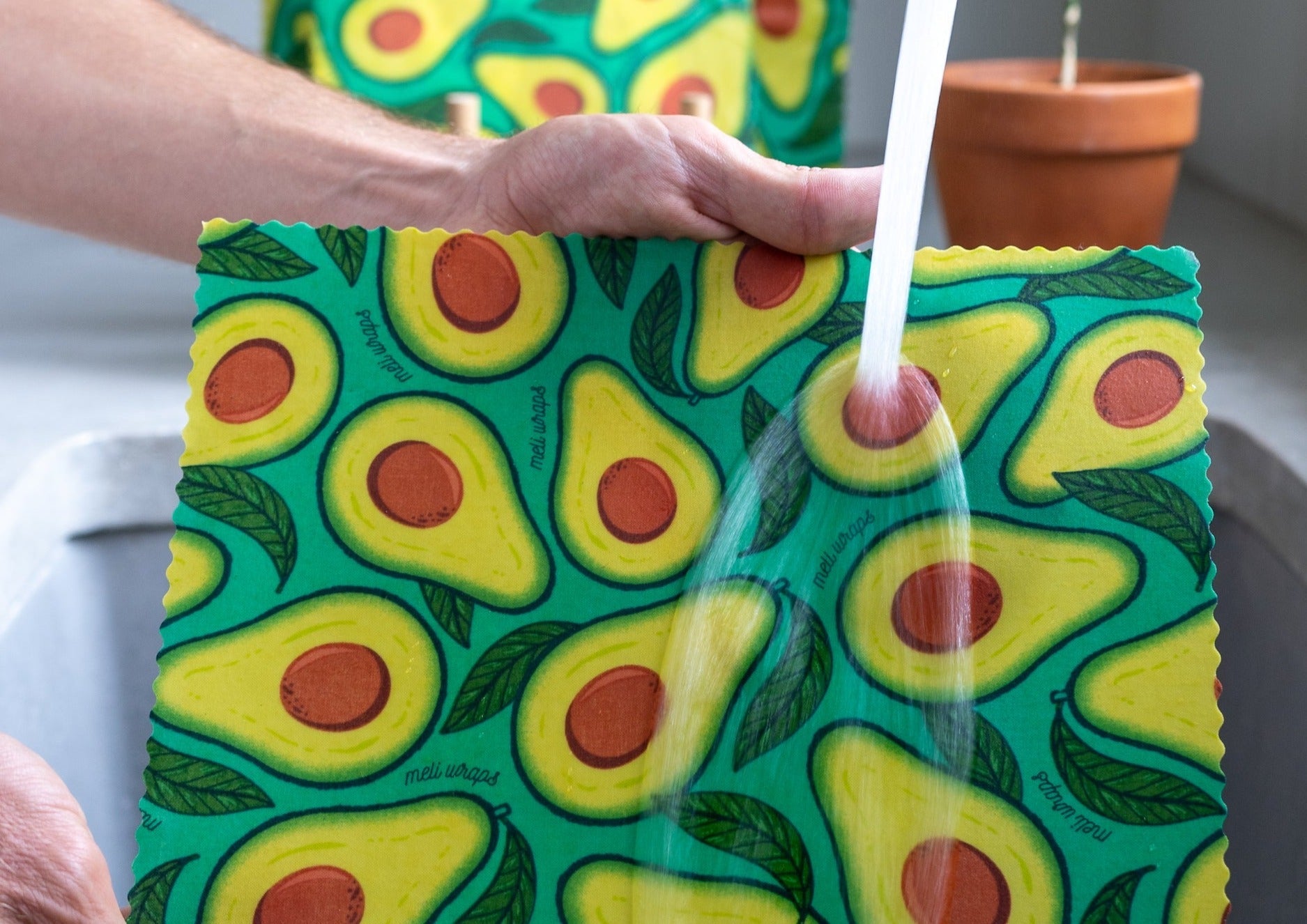 Avocado-patterned cloth being used to pour a liquid.