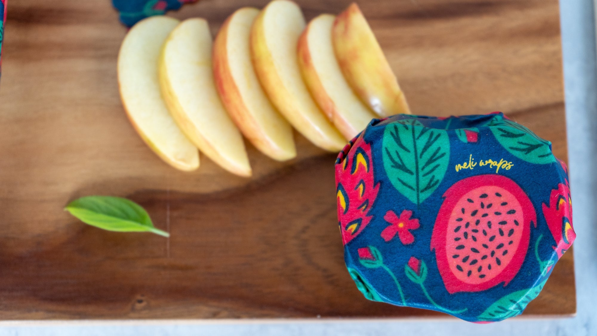 Colorful fruit-patterned product on a wooden surface with sliced peaches