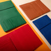 Four colorful leather card holders (green, brown, red, blue) on a beige background.