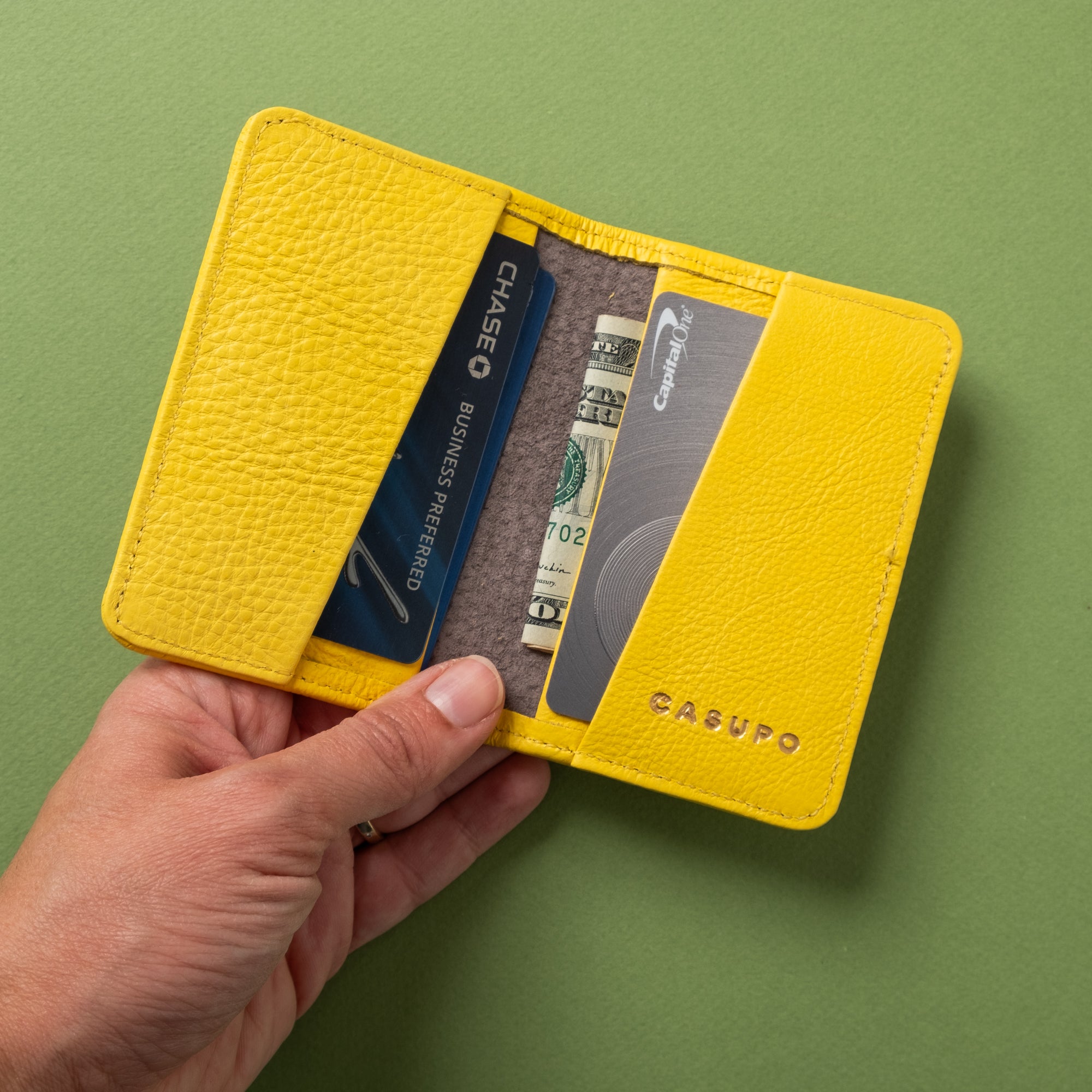 Yellow wallet with cards and cash on a green background