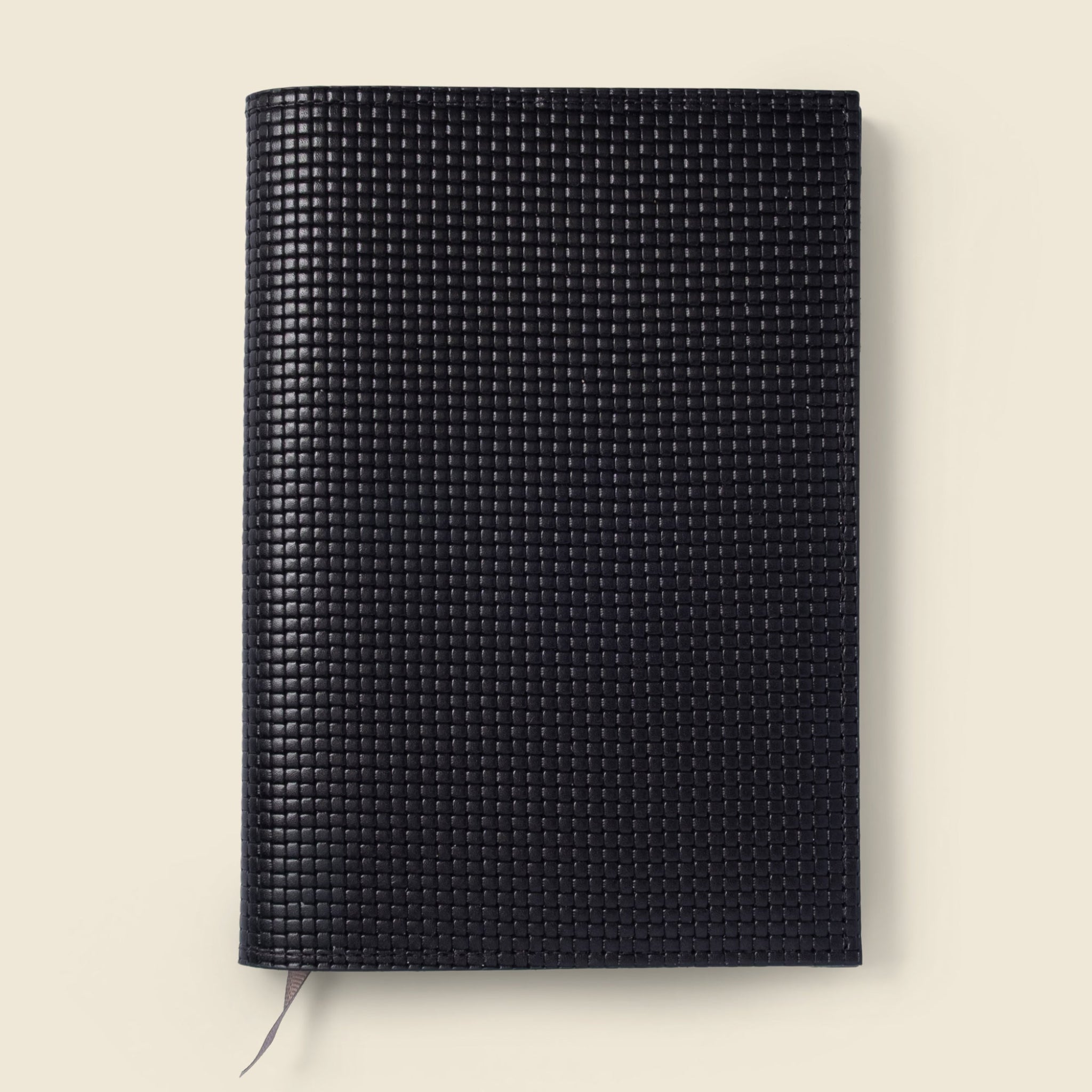 Black textured notebook on a beige background