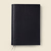 Black textured notebook on a beige background