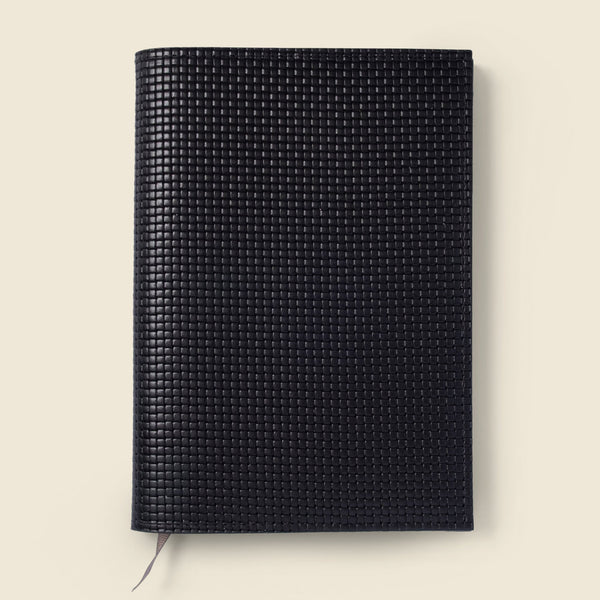 Black textured notebook on a beige background