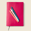 Pink notebook with colorful pens on a beige background