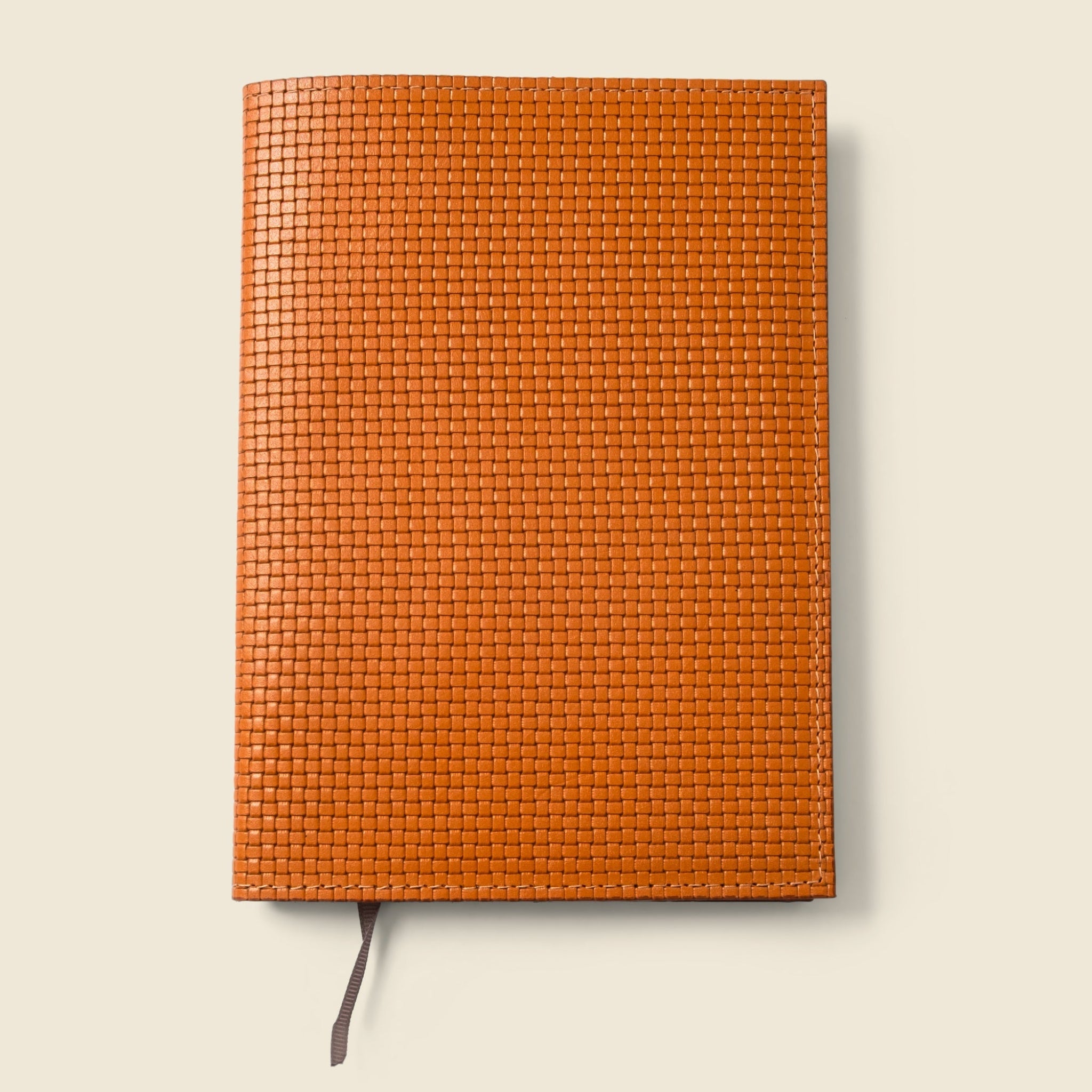 Orange woven leather notebook on a beige background