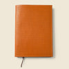 Orange woven leather notebook on a beige background