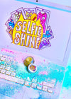 Colorful 'Selfie Shine' product with a keyboard and phone on a light background