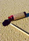Rollerball bottle with a droplet of liquid on sand