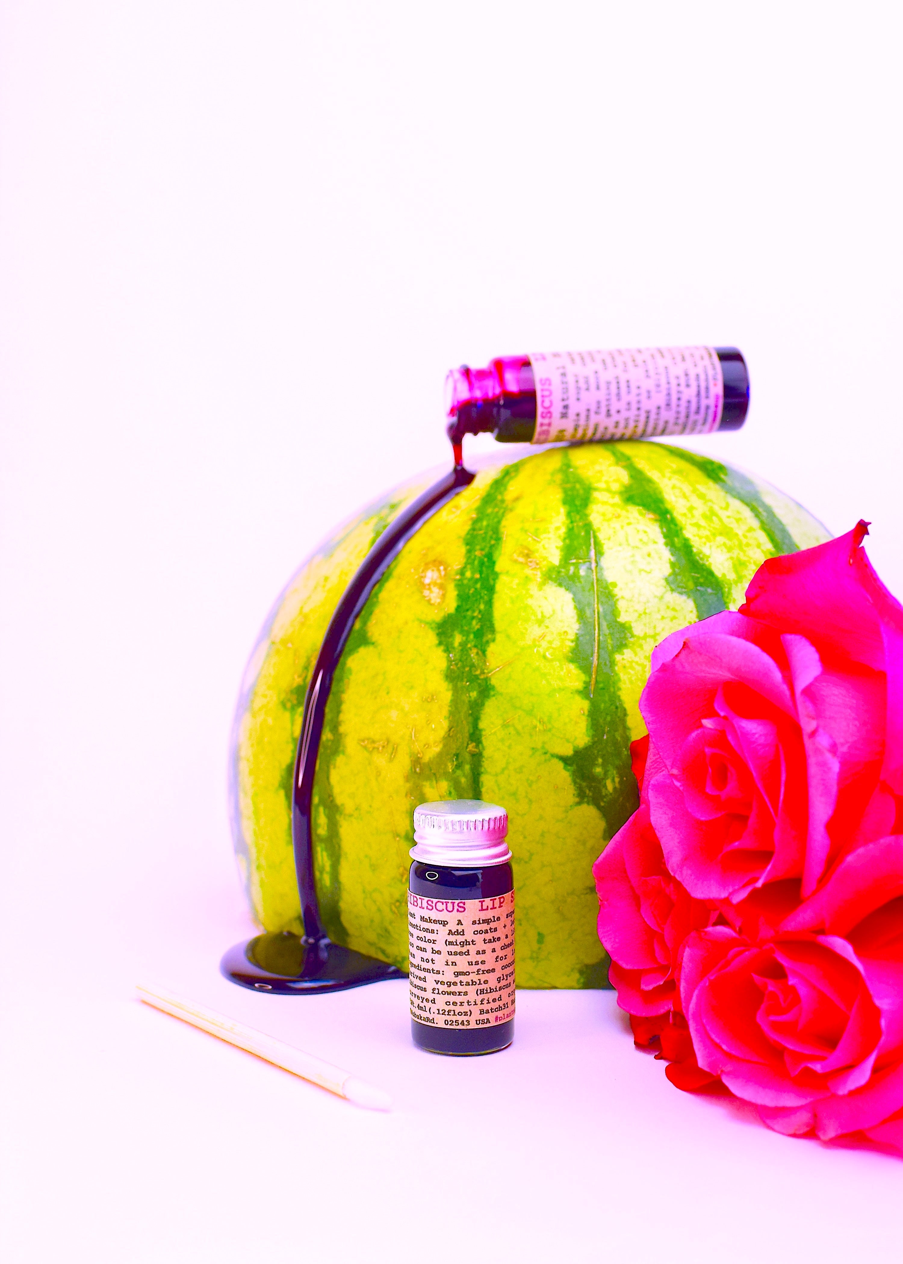 Watermelon with a pink rose and small bottle on a white background