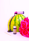 Watermelon with a pink rose and small bottle on a white background