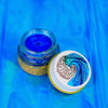 SEA Creature blue spirulina lip balm in a glass jar by Plant Makeup, sitting on a natural surface