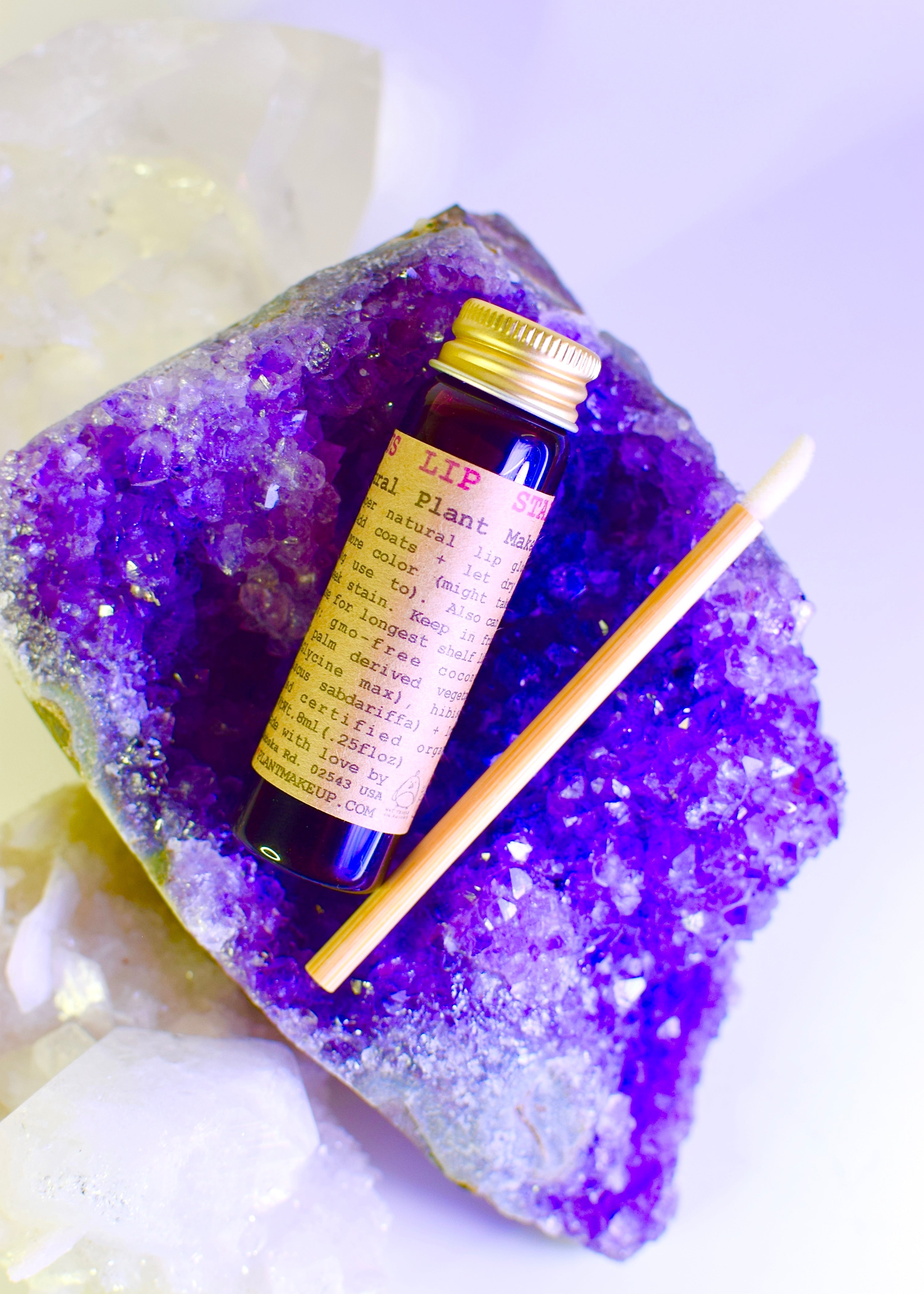 Small bottle with a yellow label on a purple crystal with a white background