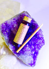 Small bottle with a yellow label on a purple crystal with a white background