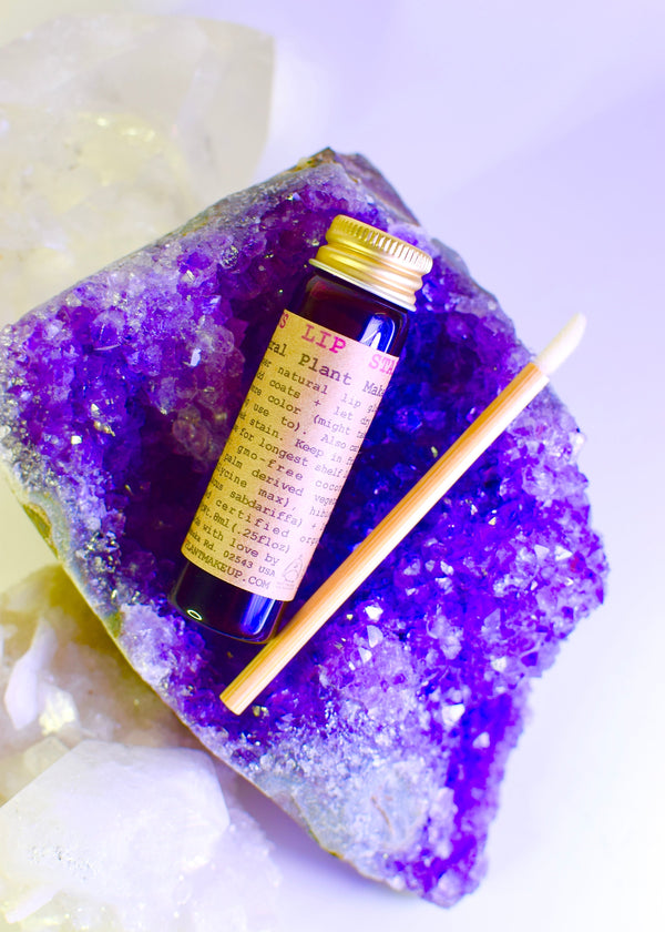 Small bottle with a yellow label on a purple crystal with a white background