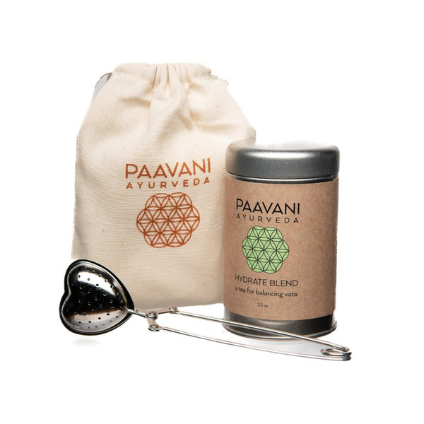 Paavani Ayurveda product set with a tea bag, container, and strainer on a white background