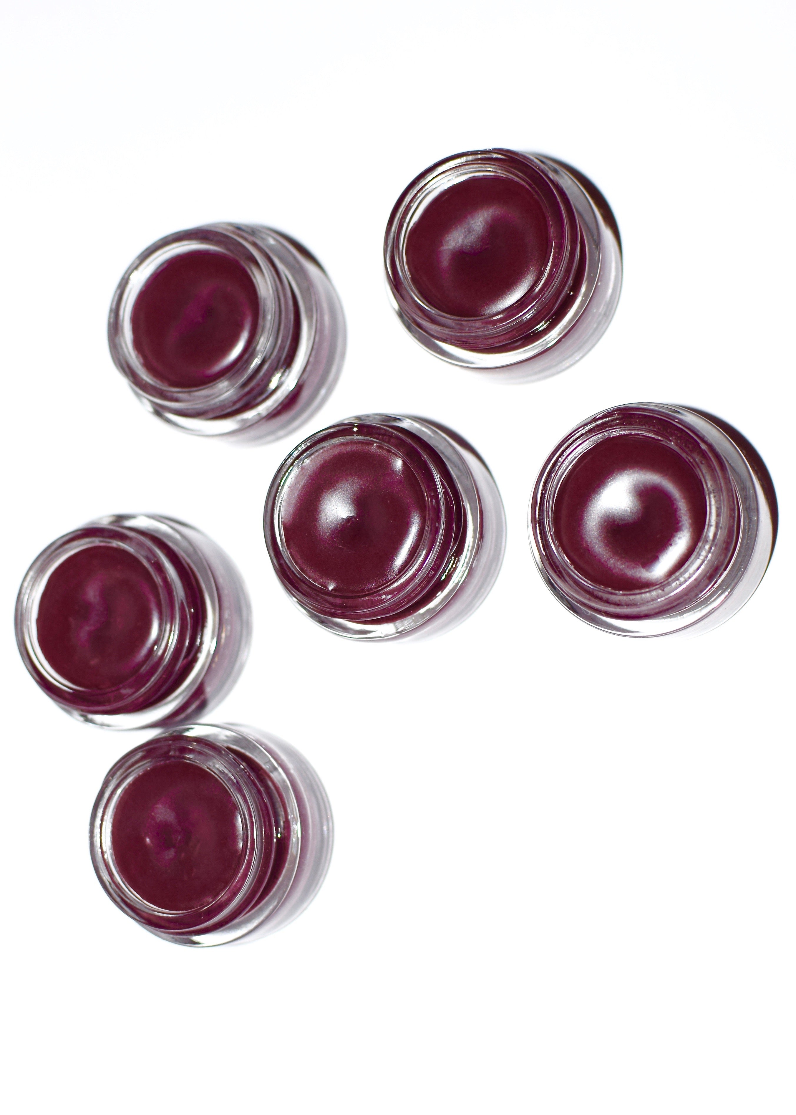 Set of six small containers with a dark red substance on a white background
