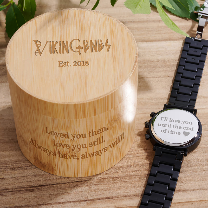 Bamboo box with engraved text and a smartwatch on a wooden surface