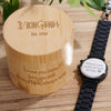 Bamboo box with engraved text and a smartwatch on a wooden surface