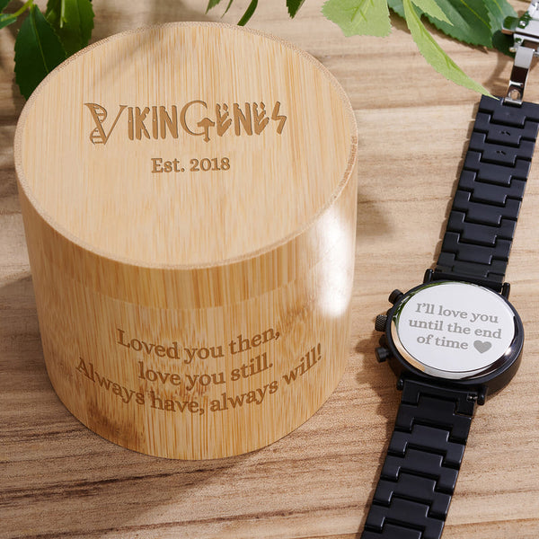 Bamboo box with engraved text and a smartwatch on a wooden surface