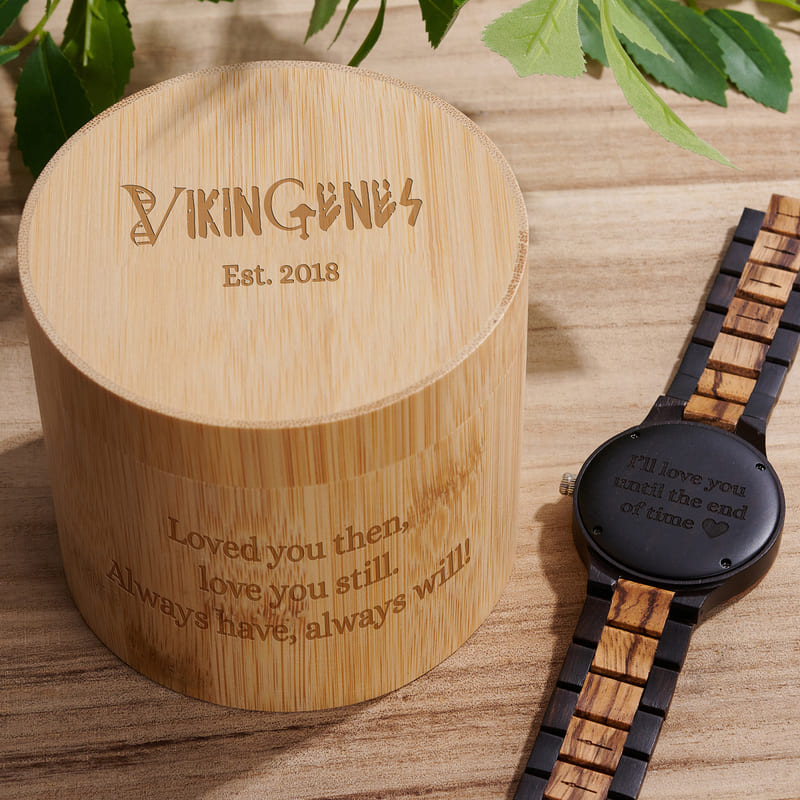 Wooden watch and engraved wooden box on a wooden surface with 'Vikingens' branding.