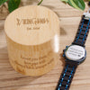 Wooden box with engraved text and a watch on a wooden surface